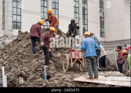Itinerant female workers shovelling earth on construction site, Shanghai, China Stock Photo