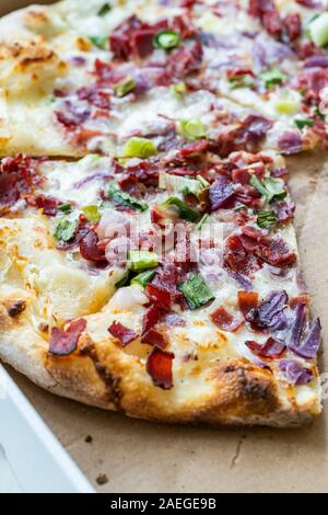 Flammkuchen Pizza Slices / Traditional Tarte Flambee with Creme Fraiche, Cream Cheese, Bacon and Red Onions in Box. Traditional Fast Food. Stock Photo
