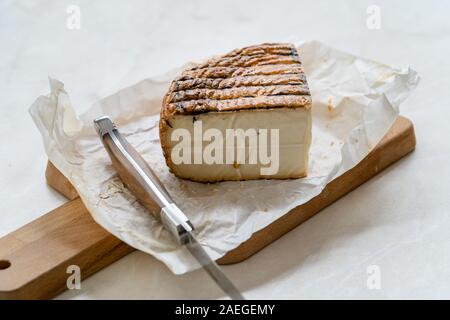 Triangle Cut Whole Smoked Cheese with Knife and Paper Sheer on Wooden Board. Organic Food. Stock Photo