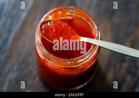 Red Hot Chili Pepper Sauce for Artisan Cheese made with Vinegar and Sugar in Glass Bowl with Spoon. Organic Food. Stock Photo