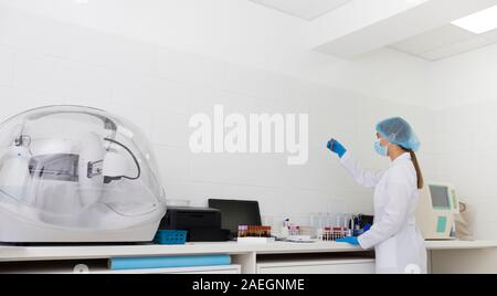 Young woman scientist in protective clothes making researches Stock Photo