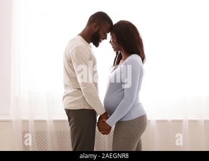 Black pregnant couple bonding at home, happy together Stock Photo