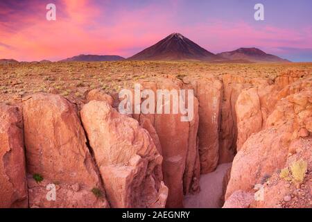 A narrow canyon with a volcano in the distance. Photographed at the foot of Volcan Licancabur in the Atacama Desert, northern Chile, at sunset. Stock Photo