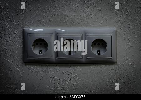 Triple electrical outlet. Black and white dramatic vignette shot. Front view. Stock Photo