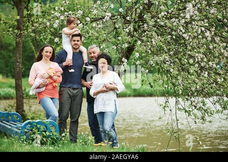 Family photo. Full length portrait of cheerful people standing outdoors together near the lake Stock Photo