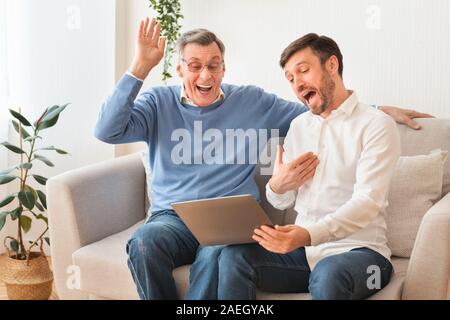 Mature Man And Senior Father Using Laptop Laughing Sitting Indoor Stock Photo
