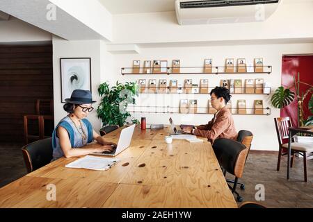 Group of young Japanese professionals working on laptop computers in a co-working space. Stock Photo