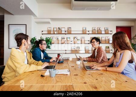 Group of young Japanese professionals working on laptop computers in a co-working space. Stock Photo