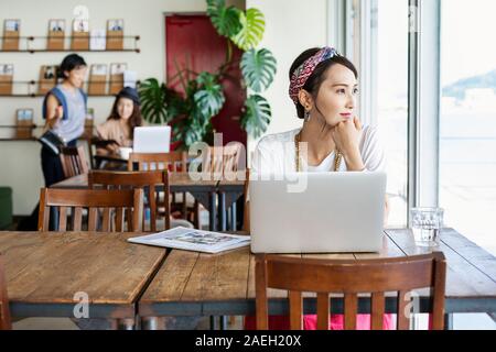 Group of young Japanese professionals working on laptop computers in a co-working space. Stock Photo