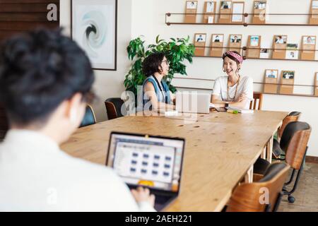 Group of young Japanese professionals working on laptop computers in a co-working space. Stock Photo
