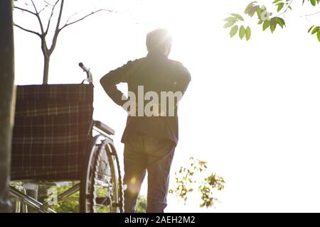 rear view of asian senior man sitting in wheel chair