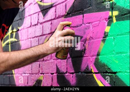 Male graffiti artist staying his own design onto a black wall Stock Photo