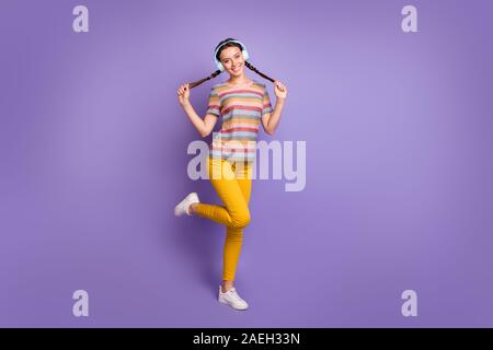 Full body photo of positive cute teenager youth girl music lover enjoy spring free time listen radio sound songs touch braids wear striped t-shirt Stock Photo