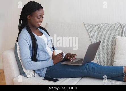 Girl Sitting On Sofa With Laptop Browsing Job Opportunities Online Stock Photo