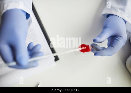 Close-up of doctor in protective gloves holding pipette and analyzing blood samples at the table Stock Photo