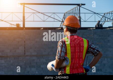 Backside Engineer Asia smart handsome and holding the digital blueprint in constructions site Stock Photo