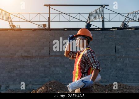 Engineer Asia smart handsome and holding the digital blueprint in constructions site Stock Photo