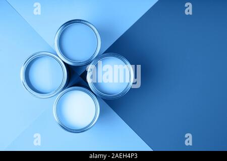 Four open cans of paint on bright symmetry background.Blue color. Place for text. Renovation concept. Stock Photo