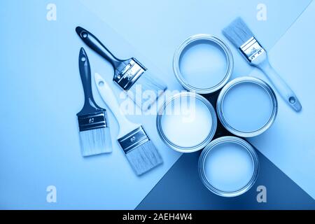 Four open cans of paint with brushes on blue background. Main color of the year 2020 in interior Stock Photo