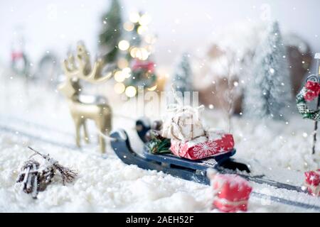 Miniature sled loaded of gifts a on snowy winter background Stock Photo