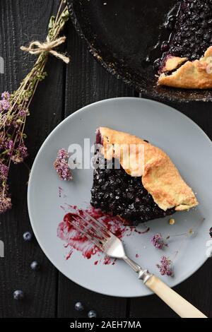 Piece of homemade blueberry galette being eaten on black background rustic style top view Stock Photo