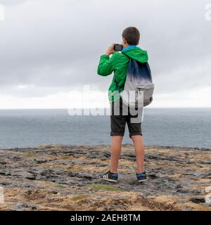 Tourist photographing at prehistoric Fort of Dun Aonghasa, Kilronan, Inishmore, Aran Islands, County Galway, Republic of Ireland Stock Photo