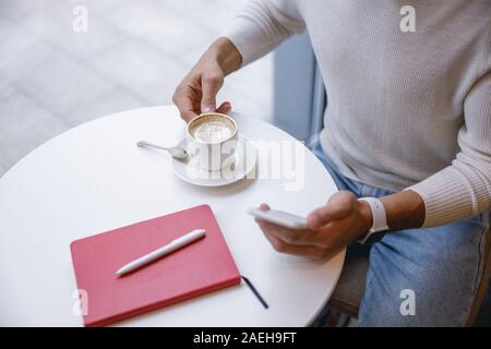 Positive delighted young man taking cup of coffee Stock Photo