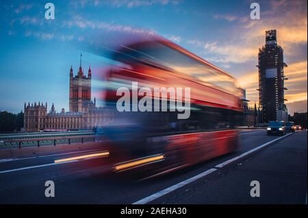 London. Classic red double decker bus crossing Westminster Bridge at sunset.