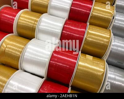 Shiny, metallic Christmas ribbon strings in red, gold, white &silver. Top view. Beautiful texture of the sparkly holiday decorations. Stock Photo