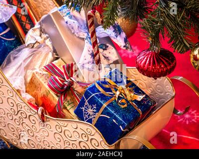 Decorative Santa Claus sleigh with coloured gifts boxes under Christmas tree. Stock Photo