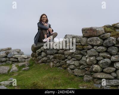 Woman sitting on stacked rocks, Achill Island, County Mayo, Ireland Stock Photo