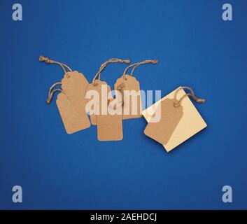 set of empty paper brown rectangular tags on a rope, price tags are on a blue trend background, top view Stock Photo