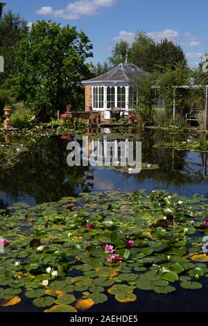 Garden summerhouse over looking ornamental pond with water lillies in english garden,England Stock Photo