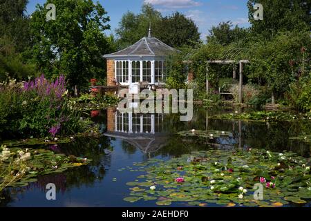 Garden summerhouse over looking ornamental pond with water lillies in english garden,England Stock Photo