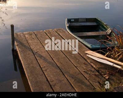 small boat next to wooden jetty on english garden lake Stock Photo