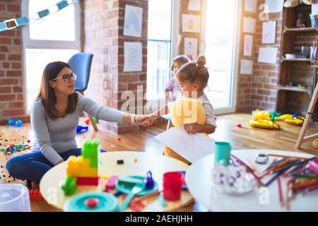 Young beautiful teacher and toddlers playing at kindergarten Stock Photo