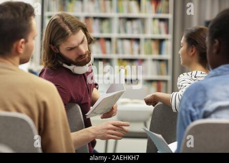 Young people discussing something and working in team while sitting at business seminar Stock Photo