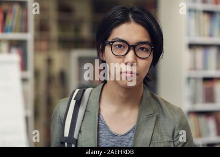 Portrait of Asian student in eyeglasses looking at camera while coming to the library Stock Photo
