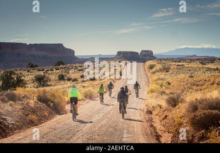 Cyclist on a road in Canyonlands National Park as they begin riding the White Rim Trail. Stock Photo