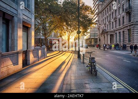 Looking towards the setting sun on Pall Mall East with bus, taxi and bicycle Stock Photo