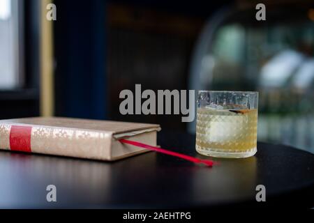 side-view of a cocktail resting on a table with a bound book Stock Photo