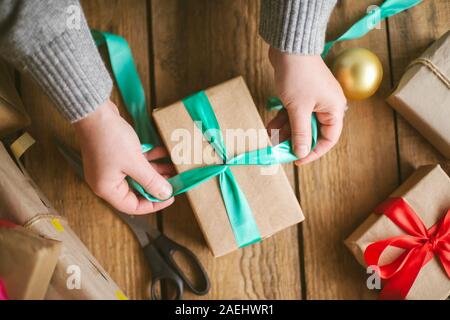 Woman wrapping christmas gifts on wooden background Stock Photo