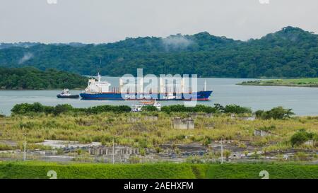 Bulk carrier ship Pacific Basin in the Gatun Lake being maneuvering by tugboats, waiting to enter the Gatun Locks Stock Photo