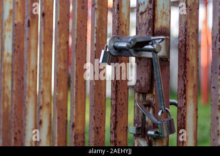 Coruna / Spain - December 08 2019: Improvised Triple padlock on a rusty metal gate Stock Photo