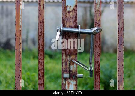 Coruna / Spain - December 08 2019: Triple padlocks on a rusty metal gate Stock Photo