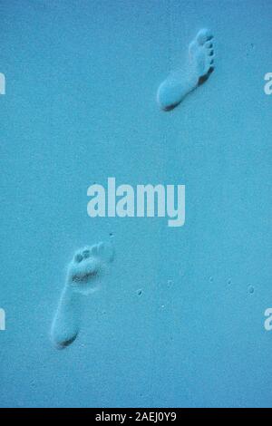 Surreal Pop art styled woman's walking footprints on the sand beach in blue color Stock Photo