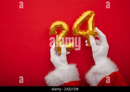 Santa hands holding 24th December gold balloons. Father Christmas background Stock Photo