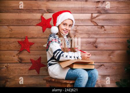 Cute child girl writing letter santa home near the Christmas tree Stock Photo