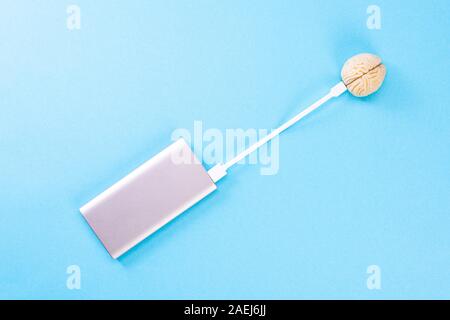 The brain on a blue background is recharged from the power bank Stock Photo