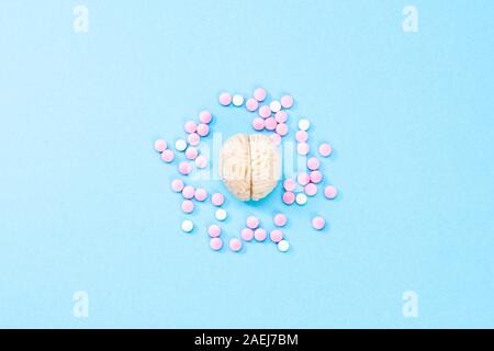 Brain on a blue background with white and pink pills. Some pills for the brain. Symbolical for medicines, psychopharmaceuticals, nootropics and other Stock Photo